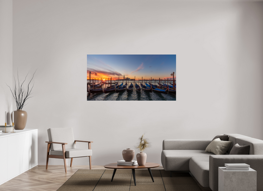 Gondels in Venetië bij zonsondergang met blauwe afdekzeilen, houten palen, San Marco-klokkentoren en warme oranje-roze lucht – romantische reisfotografie wanddecoratie.